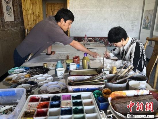 圖為2020年8月下旬，敦煌“80后”畫家張杰龍(左)在為云南麗江“學生”莫北講解敦煌壁畫的繪畫技巧。　馮志軍 攝
