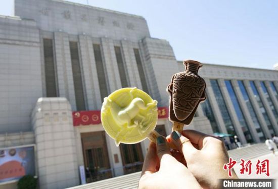 2021年7月30日，游客手拿“銅奔馬”“彩陶瓶”造型的雪糕，在甘肅省博物館前拍照打卡?！「哒?攝