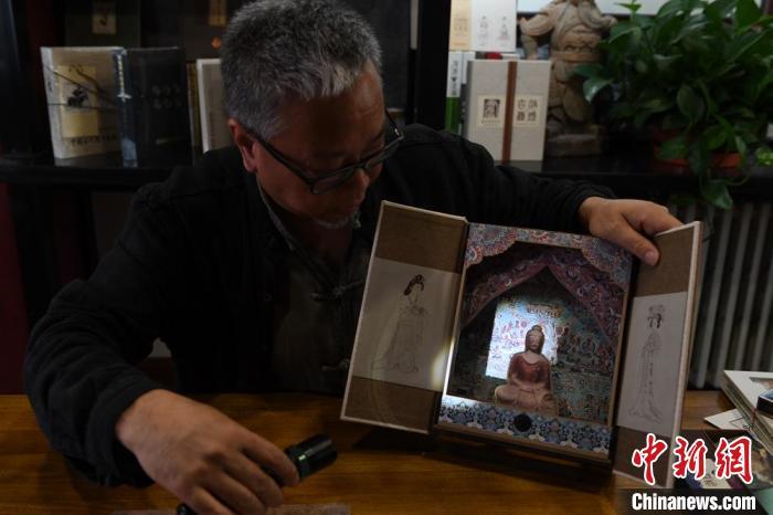 圖為讀者出版集團(tuán)讀者晉林工作室獨(dú)立出品人徐晉林，展示互動(dòng)性強(qiáng)的敦煌題材手工書。(資料圖) 楊艷敏 攝