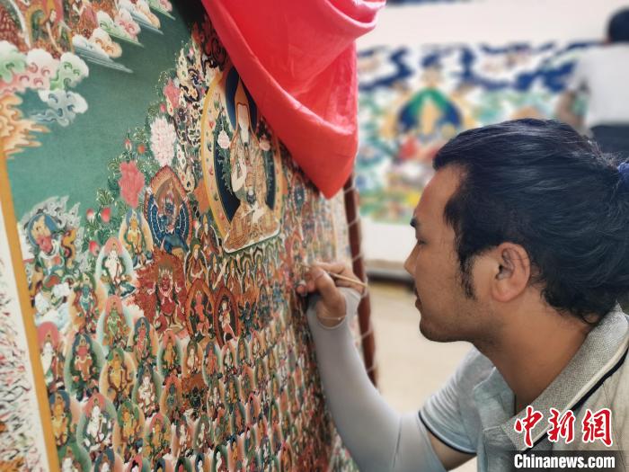 圖為更登才讓的徒弟繪畫(huà)唐卡?！?zhí)砀?攝