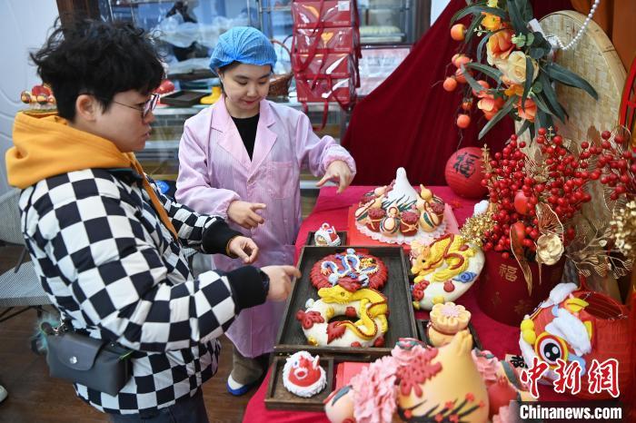 1月25日，隨著春節(jié)臨近，蘭州一花饃店“龍”元素花饃熱銷(xiāo)。圖為工作人員向顧客推薦“龍”元素花饃。九美旦增 攝</p><p>