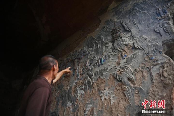7月15日，甘肅省平?jīng)鍪袥艽h百里石窟長廊羅漢洞石窟內(nèi)，該窟文保員郭建平介紹窟內(nèi)石刻彩繪壁畫。郭建平家中三代人曾自發(fā)保護(hù)羅漢洞石窟。羅漢洞石窟遺存40余個(gè)窟龕，以北魏至清代風(fēng)格為主。中新社記者 李亞龍 攝